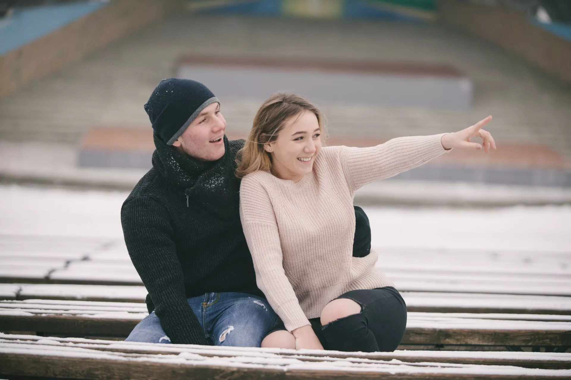 兩名使用者在戶外階梯上並肩而坐，其中一人從後方環抱，另一人伸手指向前方，地面覆有薄雪，呈現冬季外出互動情境。